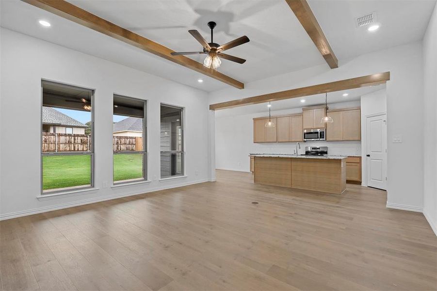 Kitchen featuring stainless steel appliances, light hardwood / wood-style floors, beam ceiling, and decorative light fixtures