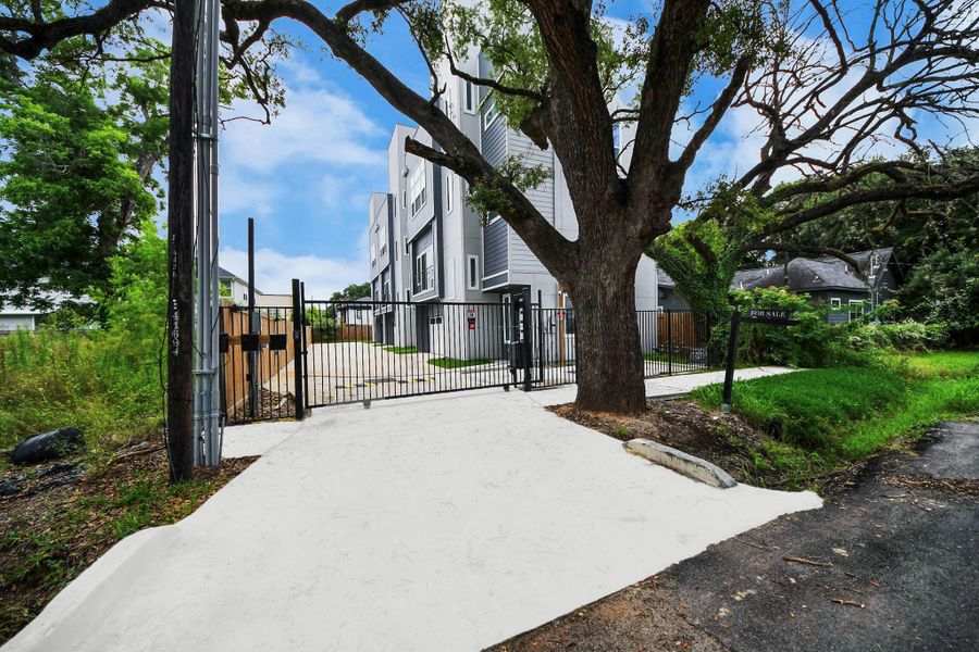 Modern multi-story home with sleek design, gated driveway, and a large tree providing natural shade. Situated in a lush, green setting. Modern multi-story home with sleek design, gated driveway, and a large tree providing natural shade. Situated in a lush, green setting.