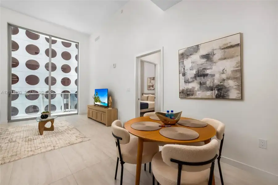 Vaulted ceilings, large-format tile flooring, and floor-to-ceiling sliding glass doors opening to an exterior balcony