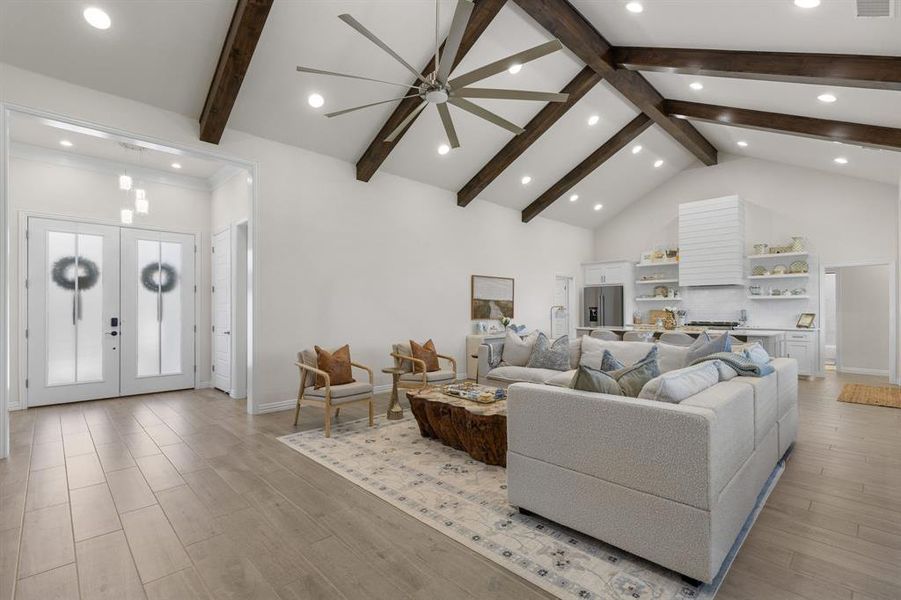 Living area with high vaulted ceiling, light wood finished floors, french doors, ceiling fan, and beam ceiling Living area with high vaulted ceiling, light wood finished floors, french doors, ceiling fan, and beam ceiling