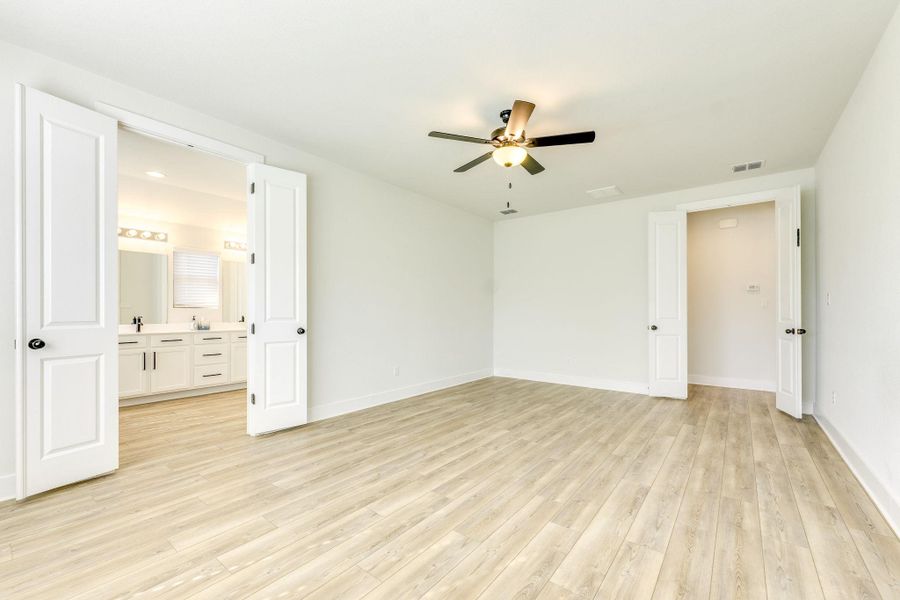Unfurnished bedroom featuring light wood-style floors, a ceiling fan, and ensuite bathroom