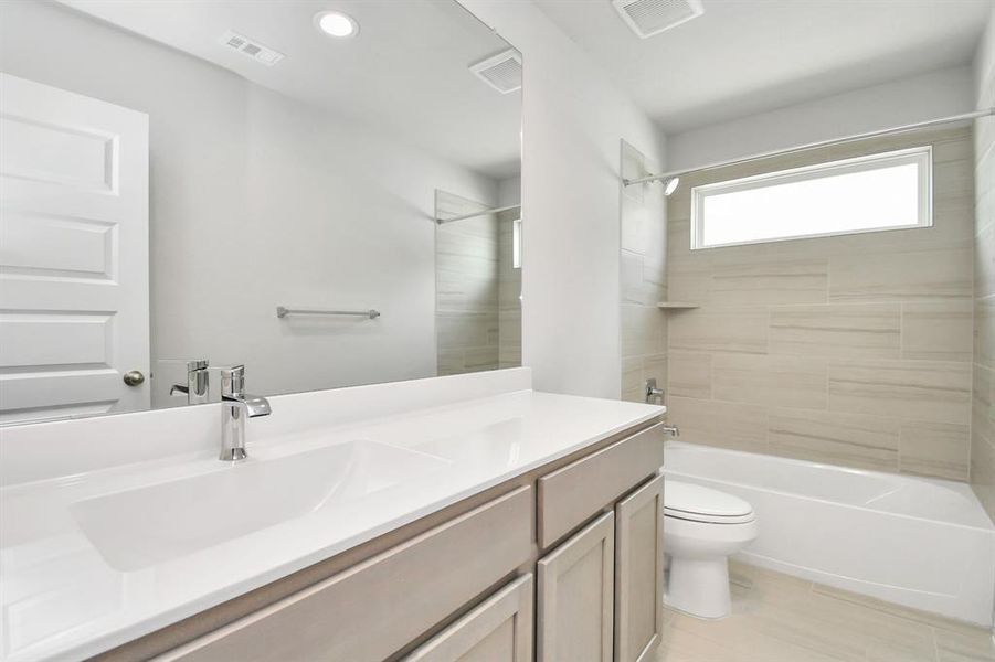 Experience sophistication in the secondary bathroom, where tile flooring complements a bath/shower combo with tile surround. Light wood cabinets complete with a beautiful light countertop, enhances the space for a truly inviting ambiance.