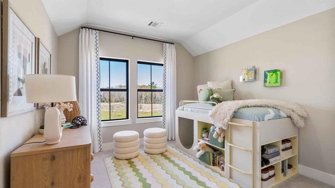 A third bedroom with two windows, decorated with bedroom furniture and wood flooring.