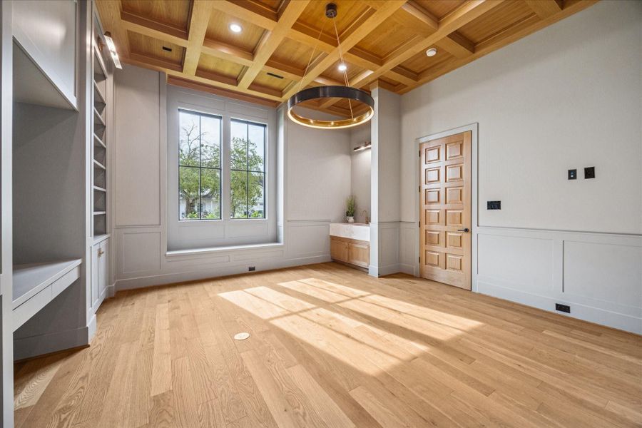 Coffered white oak ceilings introduce craftsmanship and dimension, while full-height windows frame lush green views that make workdays feel calmer. Custom built-ins blend seamlessly with wainscoting for a tailored, polished look, and a window seat creates a comfortable reading nook. A dedicated wet bar with brass fixtures elevates functionality for hosting or work-from-home routines. Soft natural light, refined finishes, and generous proportions culminate in a study that feels both inspiring and inviting. Coffered white oak ceilings introduce craftsmanship and dimension, while full-height windows frame lush green views that make workdays feel calmer. Custom built-ins blend seamlessly with wainscoting for a tailored, polished look, and a window seat creates a comfortable reading nook. A dedicated wet bar with brass fixtures elevates functionality for hosting or work-from-home routines. Soft natural light, refined finishes, and generous proportions culminate in a study that feels both inspiring and inviting.