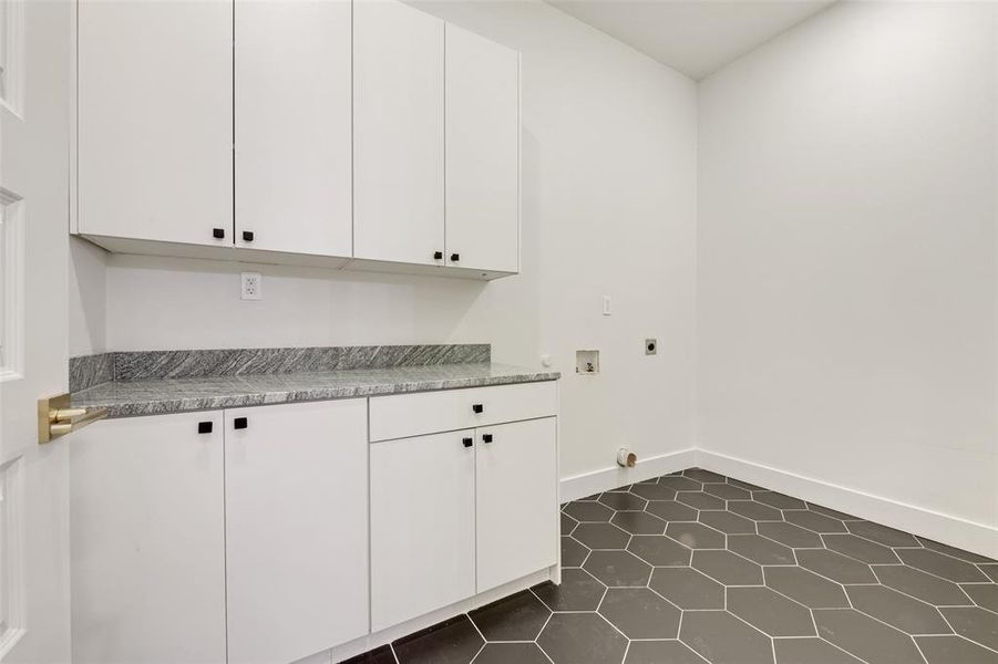 Laundry room featuring electric dryer hookup, hookup for a washing machine, dark tile patterned flooring, and cabinet space Laundry room featuring electric dryer hookup, hookup for a washing machine, dark tile patterned flooring, and cabinet space