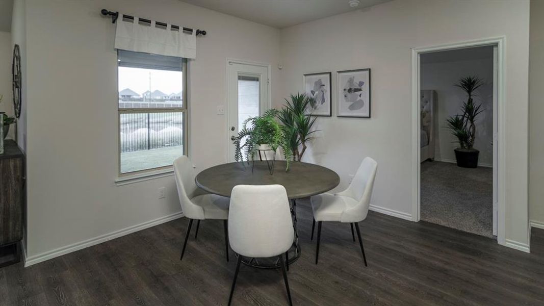 Dining area featuring wood-finish flooring and a window with a fenced backyard view Dining area featuring wood-finish flooring and a window with a fenced backyard view
