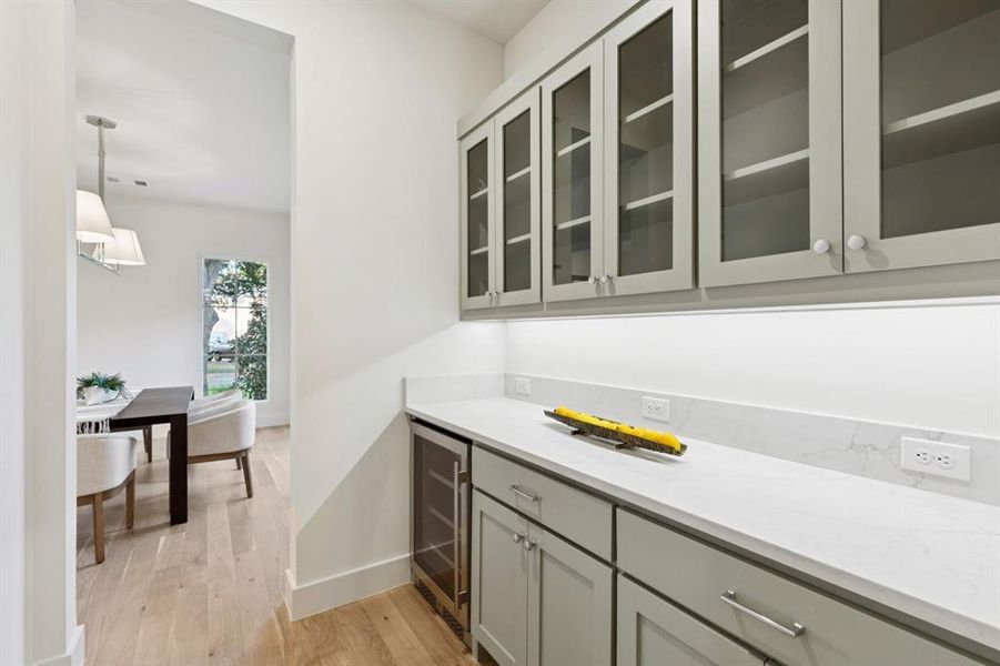 Bar featuring light wood-style floors, beverage cooler, and decorative light fixtures
