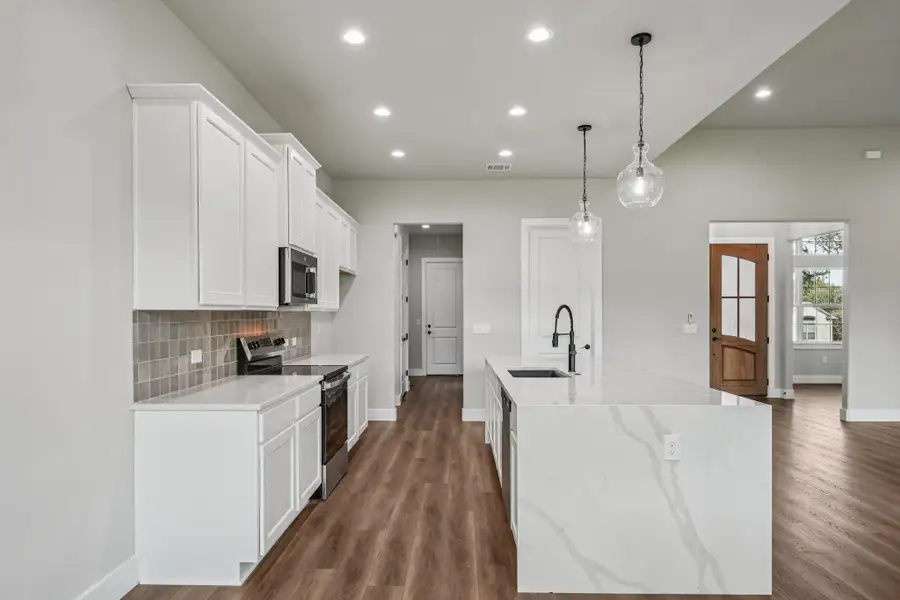 Kitchen featuring appliances with stainless steel finishes, light stone counters, recessed lighting, white cabinetry, and dark wood-style floors