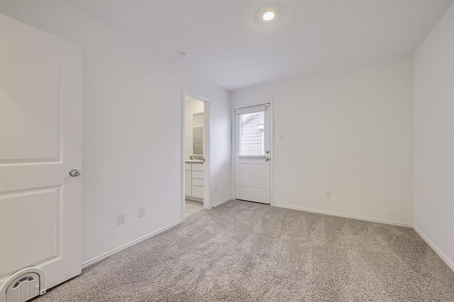 Primary bedroom with plush neutral carpeting and a dedicated full bath