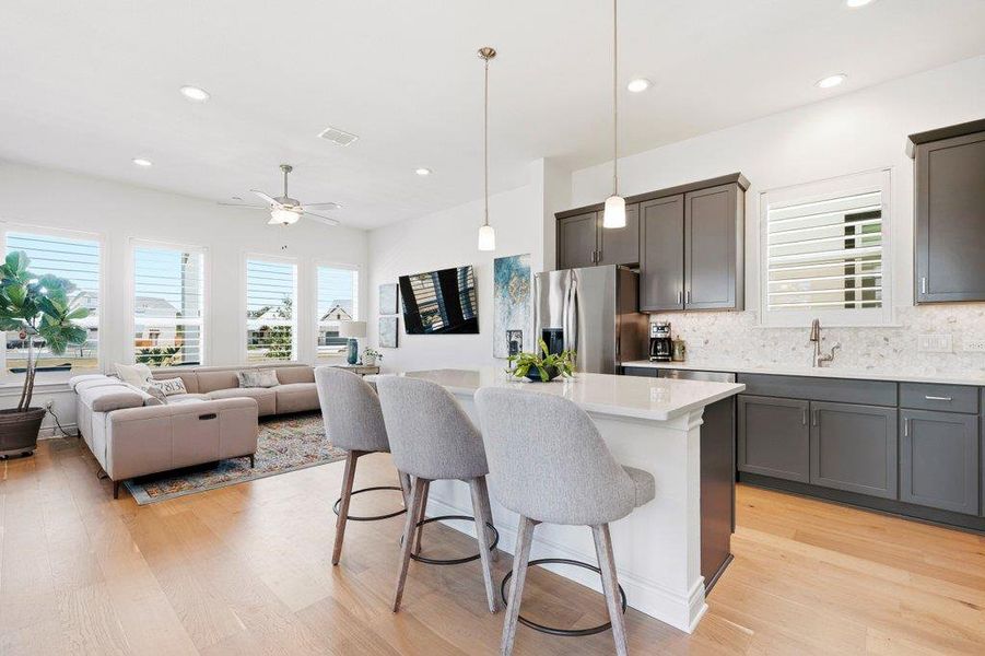 Warm hardwood floors connect a modern island kitchen with the adjacent living area. Warm hardwood floors connect a modern island kitchen with the adjacent living area.
