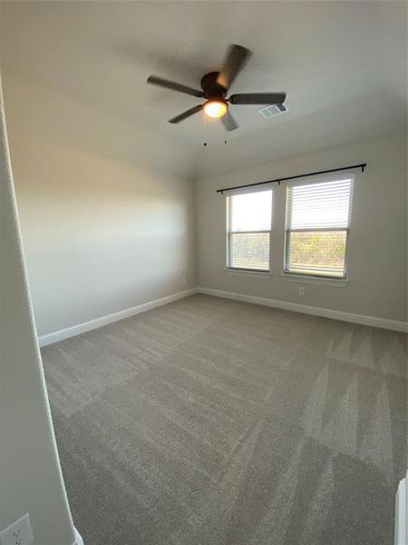 Carpeted empty room with baseboards and ceiling fan Carpeted empty room with baseboards and ceiling fan