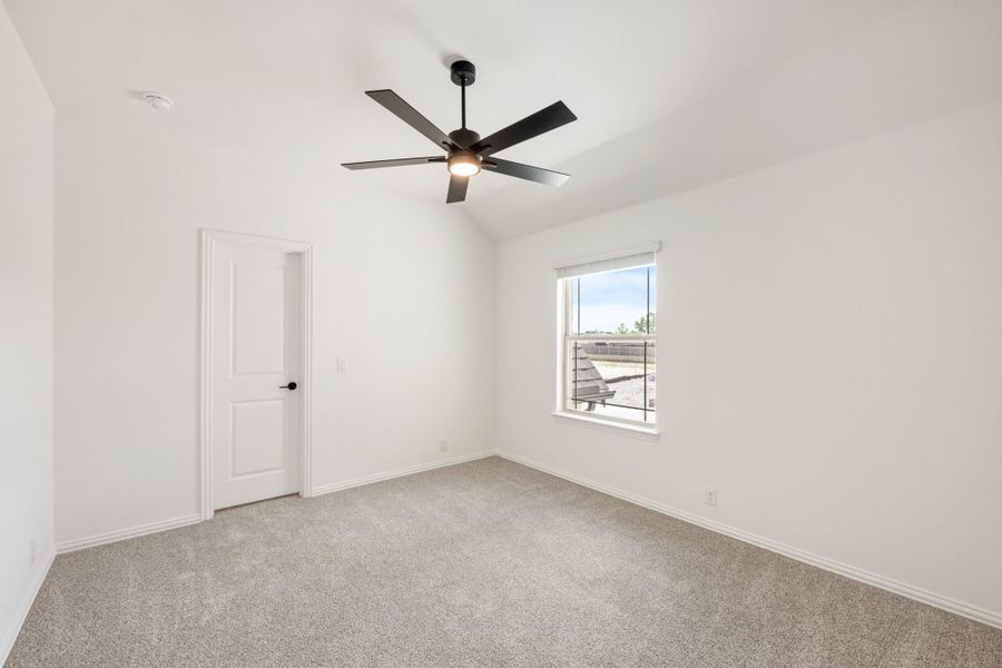 Empty bedroom with vaulted ceiling, black ceiling fan, carpet flooring, and a single window