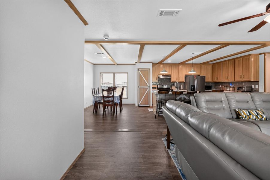 An inviting open-concept layout connects the kitchen, dining, and living areas with warm wood flooring and exposed beam ceilings.