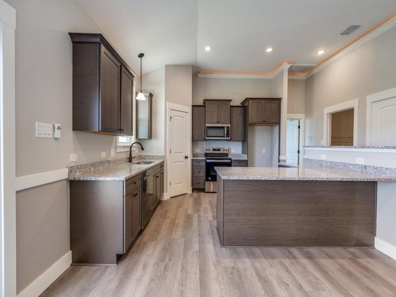 Kitchen with stainless steel appliances, a sink, visible vents, dark brown cabinetry, and crown molding