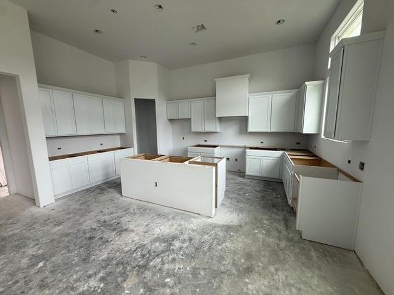 A spacious kitchen with white cabinetry and a large center island awaits your personal touch.
