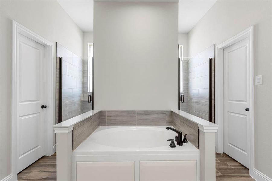 Full bath featuring a garden tub, wood finished floors, and a stall shower Full bath featuring a garden tub, wood finished floors, and a stall shower