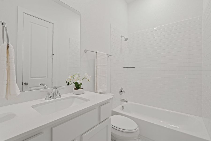 This full bathroom is located inside the bedroom, perfect place for guests to get ready while visiting. It features beautiful quartz countertops, white cabinets, large mirror, and a spacious tub an shower with subway tile surround!