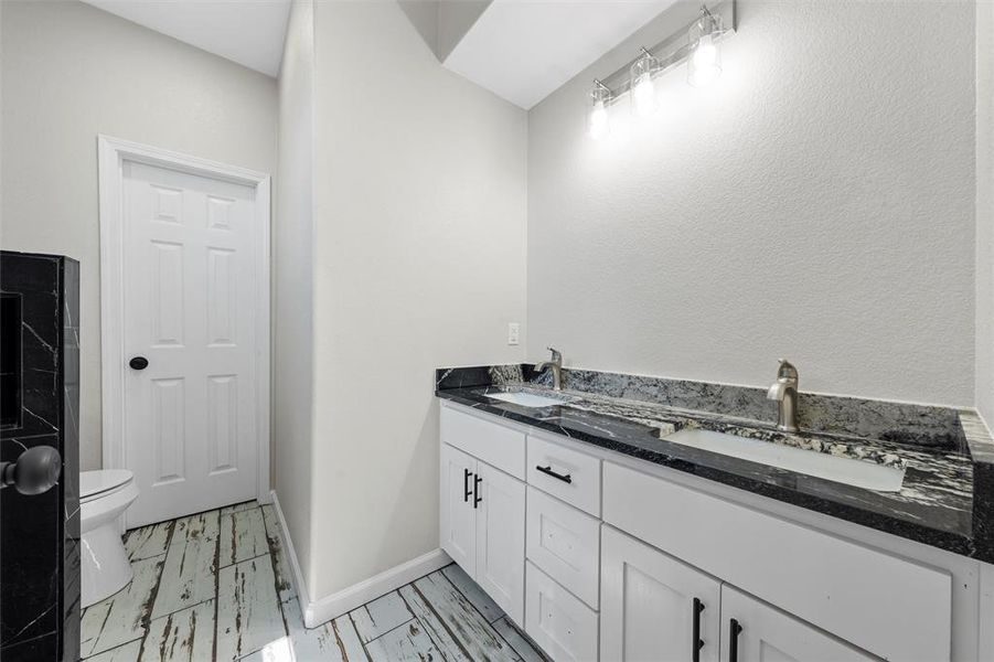 Full bath featuring double vanity and a textured wall Full bath featuring double vanity and a textured wall