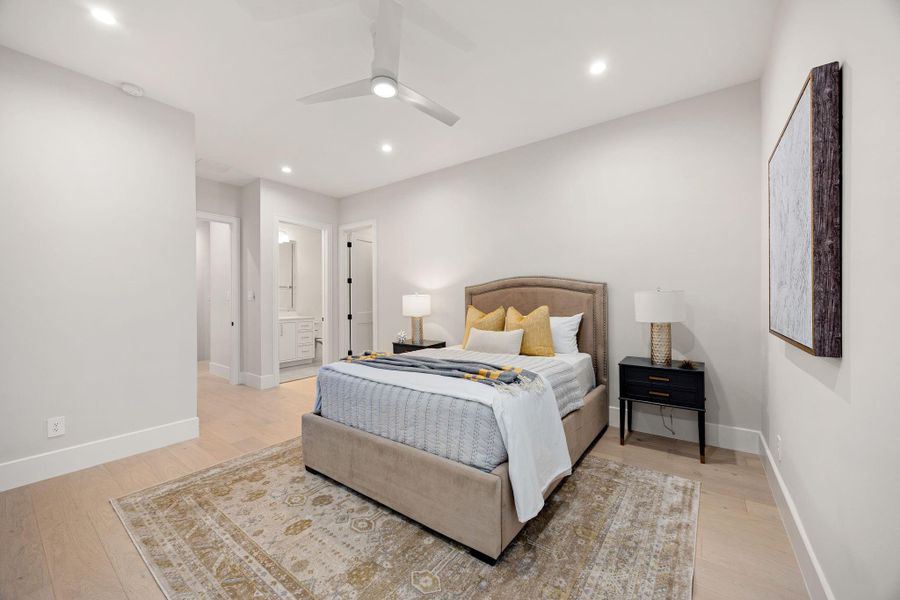 A spacious and serene bedroom retreat designed with comfort in mind, featuring soft neutral tones, warm wood flooring, and a cozy layout. The room flows effortlessly into the ensuite bath for added convenience. The highlight of this space is the private ensuite access, offering a seamless connection to a beautifully appointed bathroom for everyday ease and comfort.