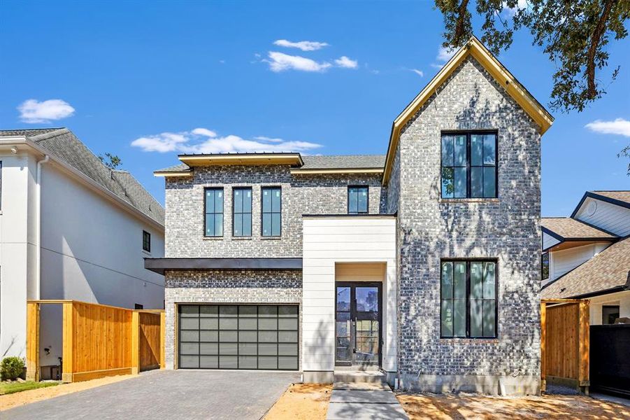 Contemporary garage door with privacy glass. Pavered driveway.  Double door entry. Brick and artisan board exterior. Construction picture taken October 17, 2024.