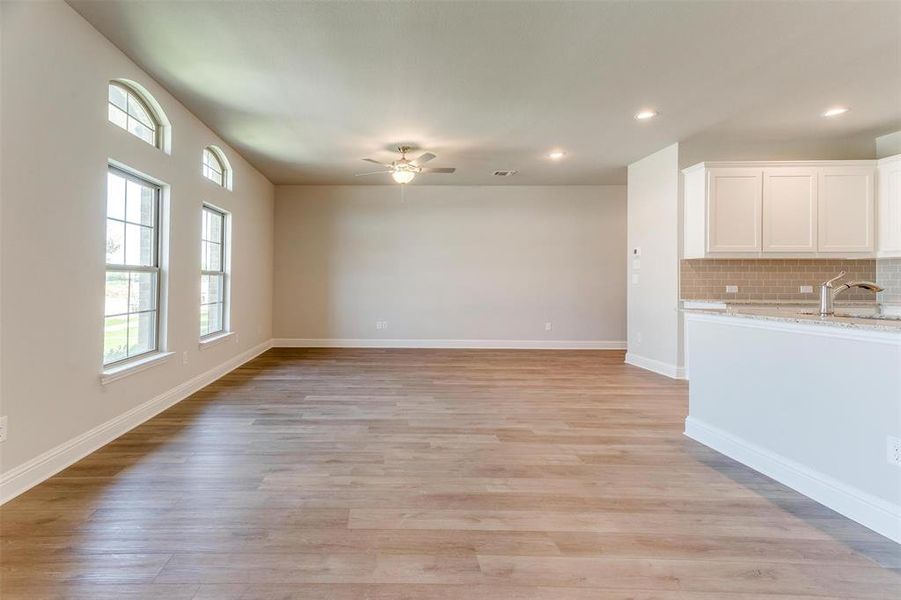 Unfurnished living room with sink, ceiling fan, and light wood-type flooring