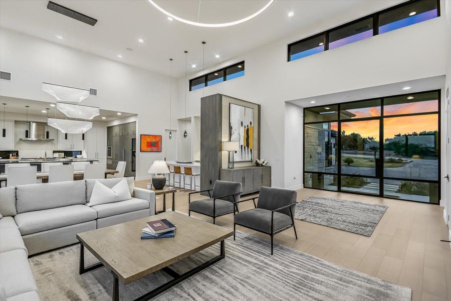 Living area featuring recessed lighting, light wood finished floors, and a high ceiling Living area featuring recessed lighting, light wood finished floors, and a high ceiling
