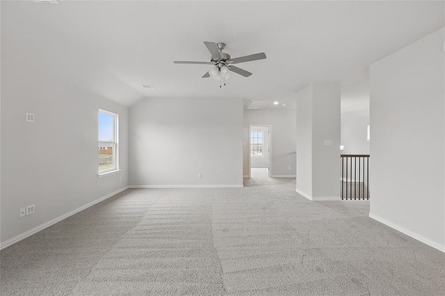 Empty room featuring attic access, light carpet, and ceiling fan