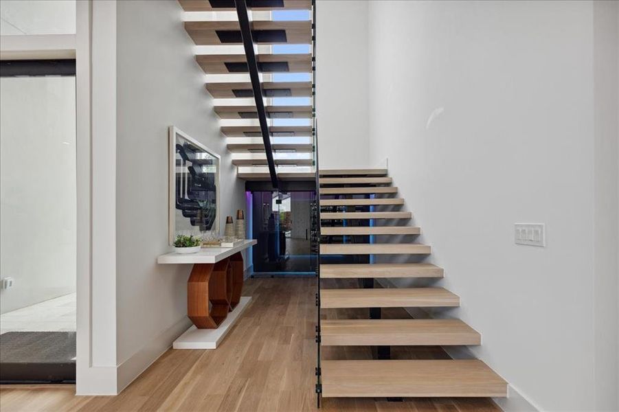 Stairway with wood-type flooring and a towering ceiling