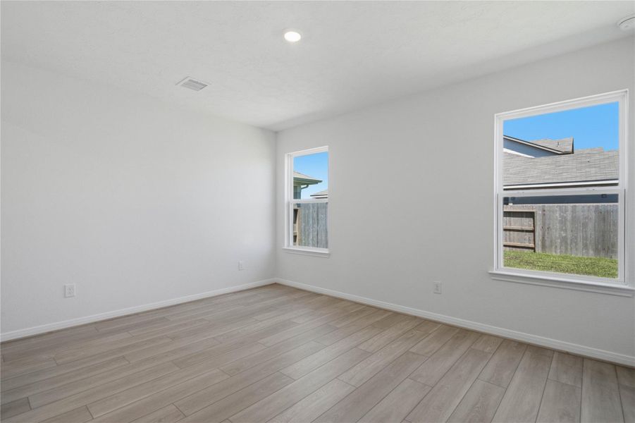 Relax and unwind after a long day in this impressive primary suite! This generously sized room offers vinyl plank flooring, neutral-toned paint, high ceilings, and large windows for added comfort and tranquility.