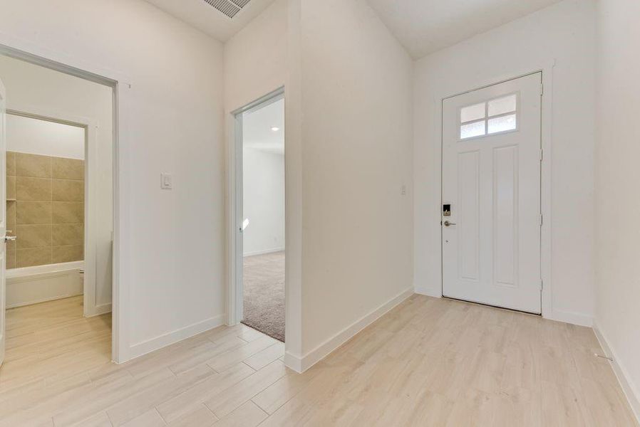 Foyer with light wood finished floors and baseboards