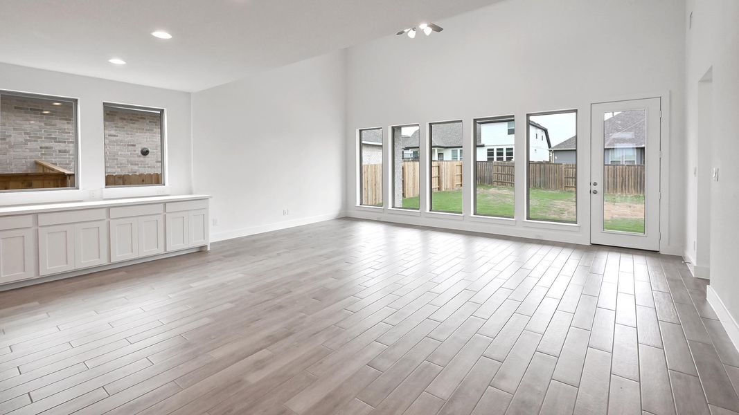 Unfurnished living room featuring light wood-style floors, baseboards, a towering ceiling, and recessed lighting