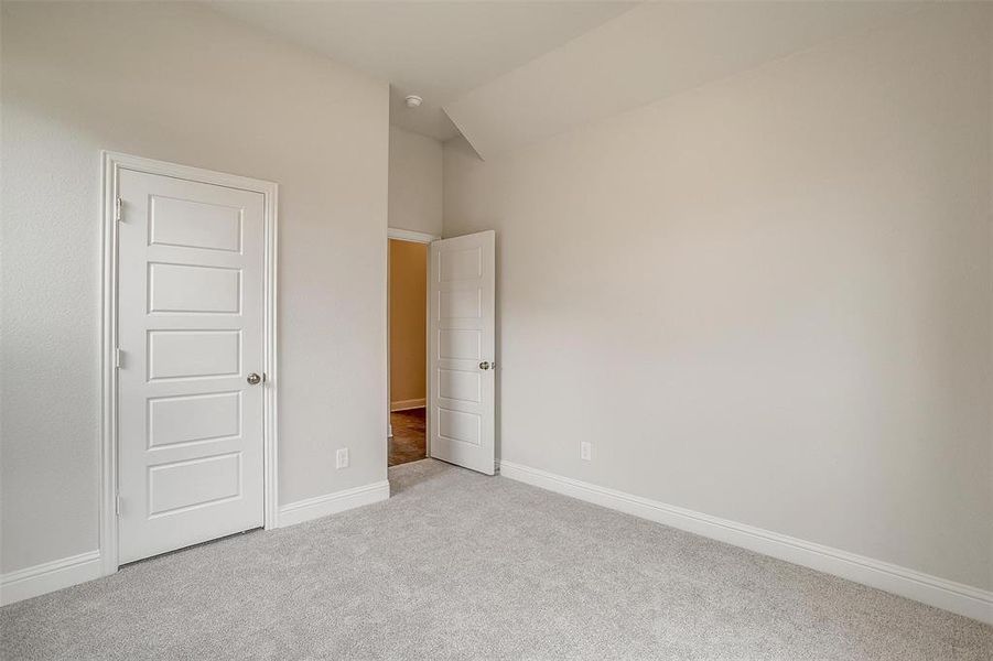 Unfurnished bedroom with vaulted ceiling and light colored carpet