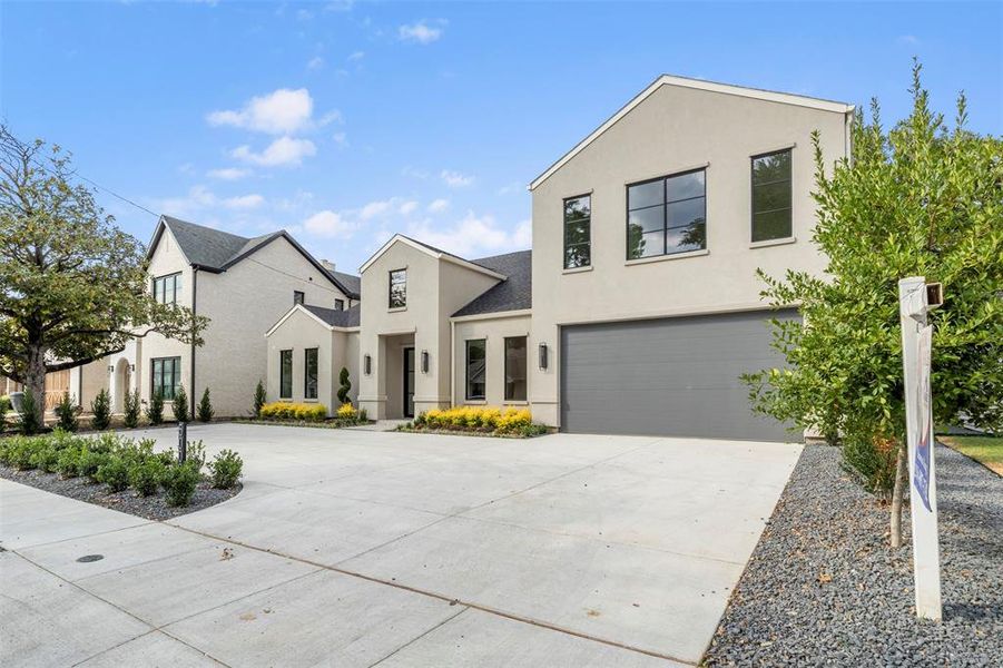 Contemporary home featuring concrete driveway, stucco siding, and an attached garage Contemporary home featuring concrete driveway, stucco siding, and an attached garage