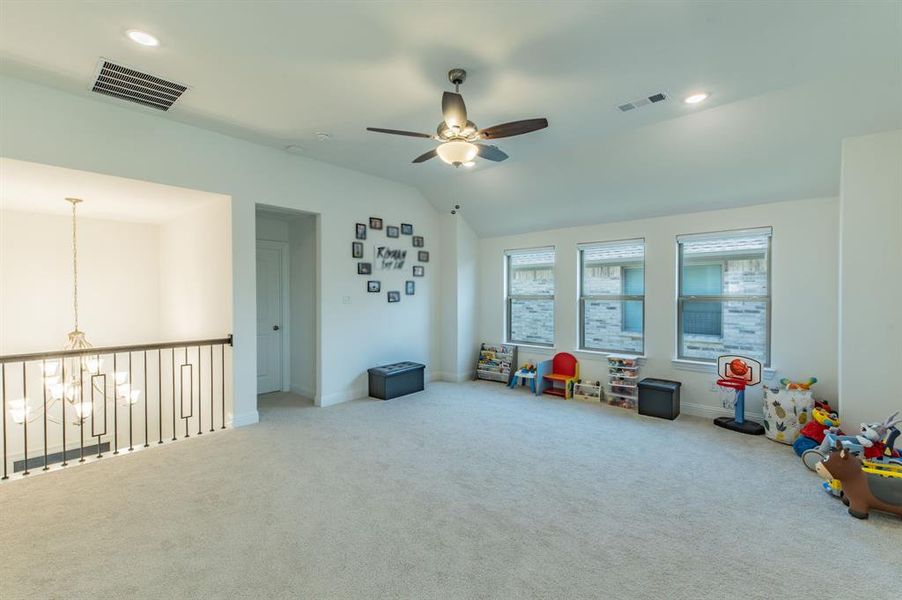 Spacious carpeted room featuring a ceiling fan, recessed lighting, and three large windows providing ample natural light