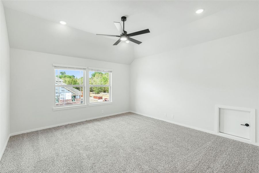 Empty bedroom with vaulted ceiling, ceiling fan, carpet flooring, and two windows