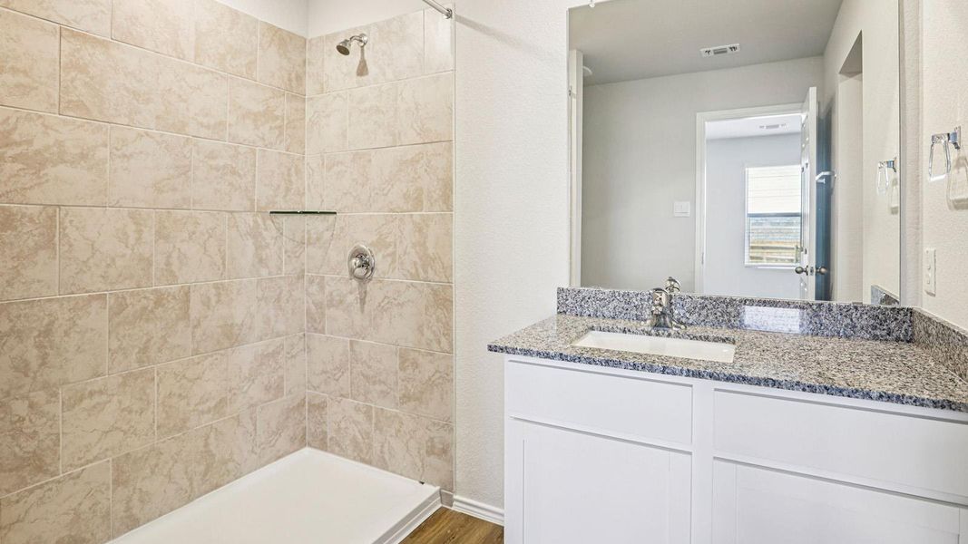 Bathroom featuring a white vanity with a granite countertop, undermount sink, and a framed mirror Bathroom featuring a white vanity with a granite countertop, undermount sink, and a framed mirror
