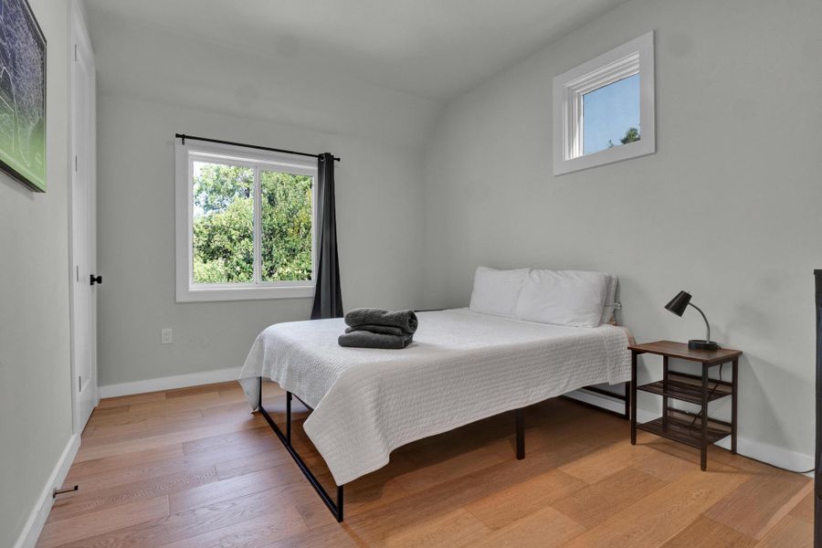 Bedroom with light wood-type flooring and vaulted ceiling