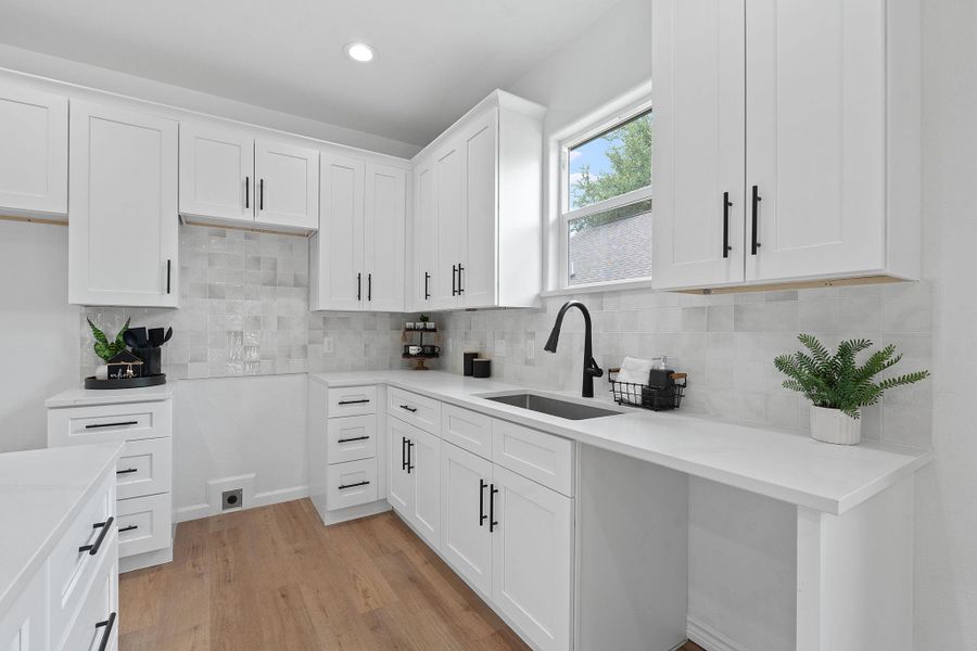 Kitchen featuring light wood finished floors, decorative backsplash, white cabinets, recessed lighting, and light countertops