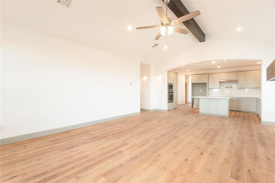 Unfurnished living room featuring arched walkways, light wood-style flooring, recessed lighting, and ceiling fan