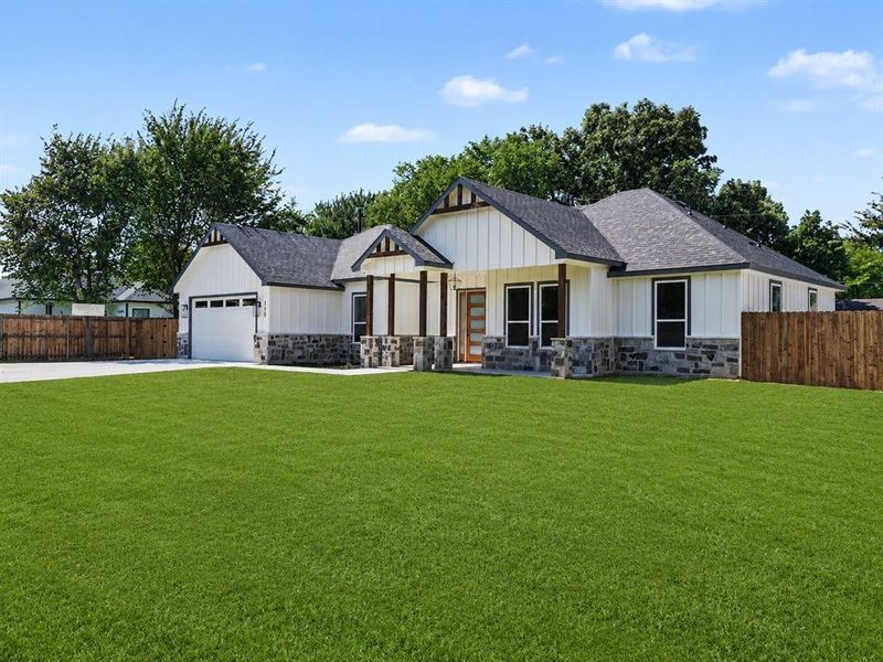 Modern farmhouse exterior featuring white vertical siding, dark shingle roofing, and stone veneer accents Modern farmhouse exterior featuring white vertical siding, dark shingle roofing, and stone veneer accents