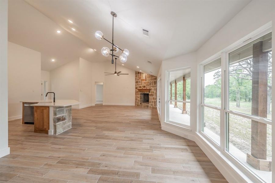 Kitchen with plenty of natural light, a chandelier, a fireplace, open floor plan, and vaulted ceiling