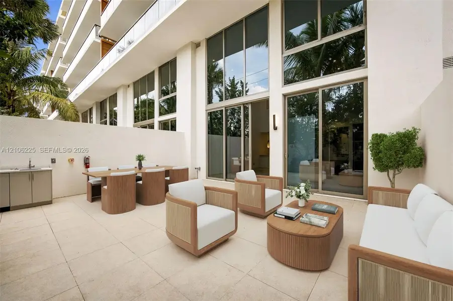 Private patio featuring light-toned stone paving, floor-to-ceiling windows, integrated exterior cabinetry, and a stainless steel sink Private patio featuring light-toned stone paving, floor-to-ceiling windows, integrated exterior cabinetry, and a stainless steel sink
