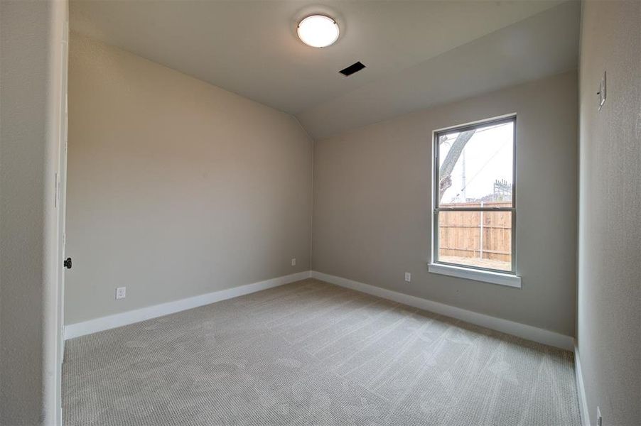 Empty room with lofted ceiling and light carpet