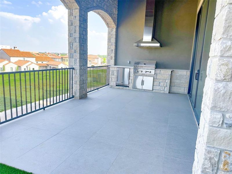 Oversized patio with custom tiled floor and built in grill.