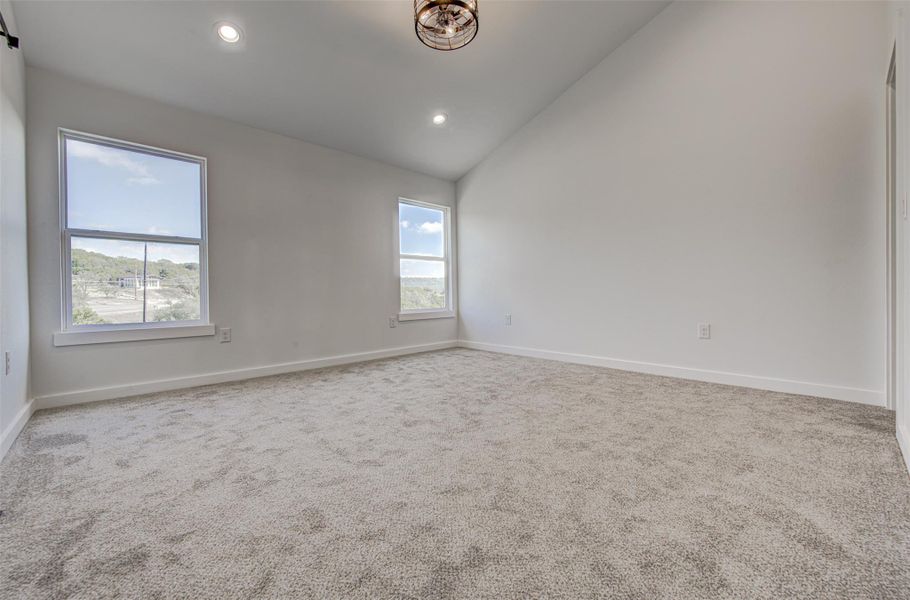 Carpeted empty room with recessed lighting and high vaulted ceiling