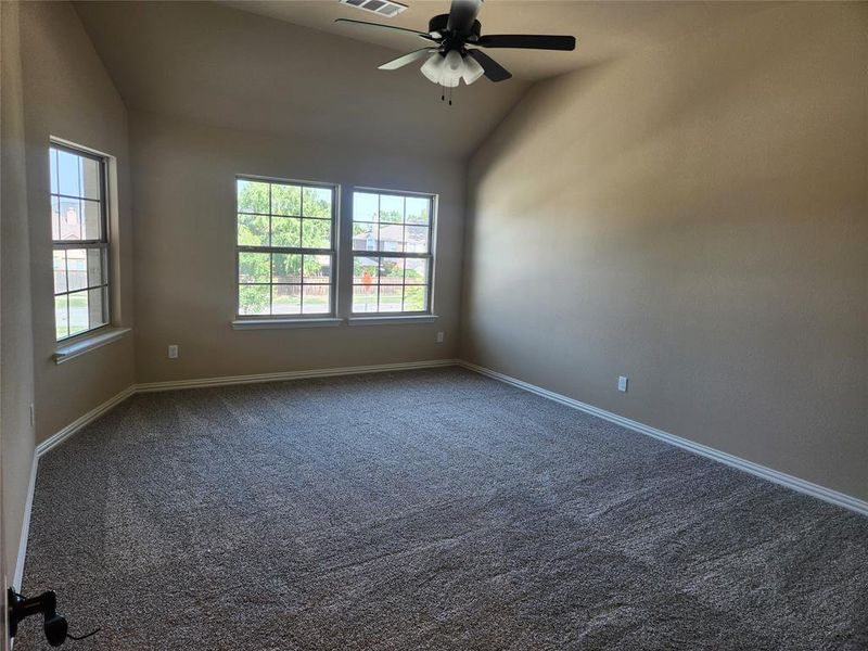 Carpeted spare room featuring ceiling fan and lofted ceiling