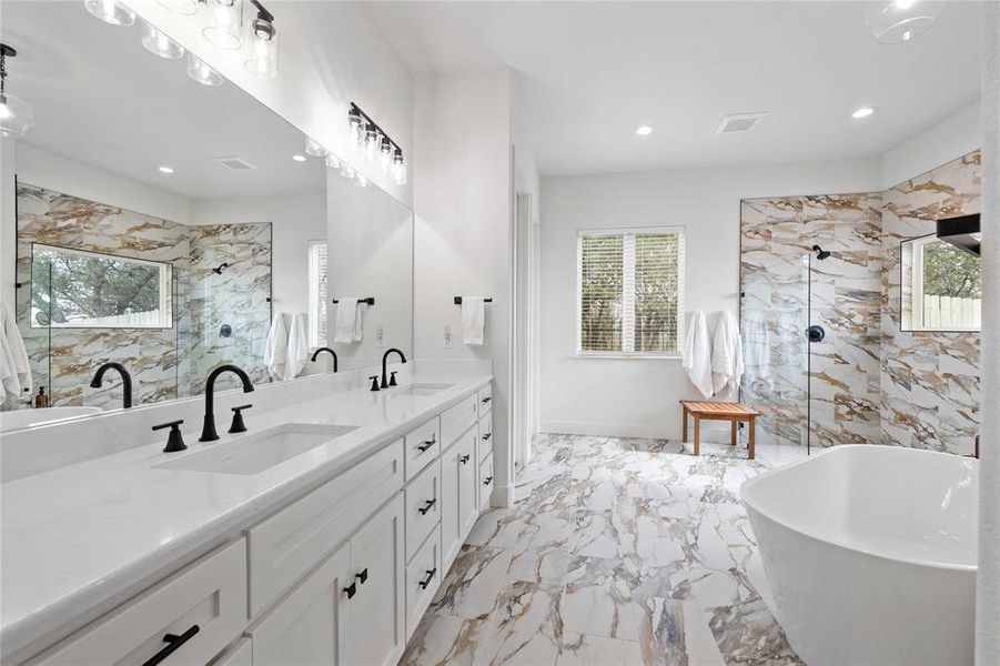 Bathroom featuring a marble finish shower, a freestanding bath, double vanity, recessed lighting, and light marble finish flooring