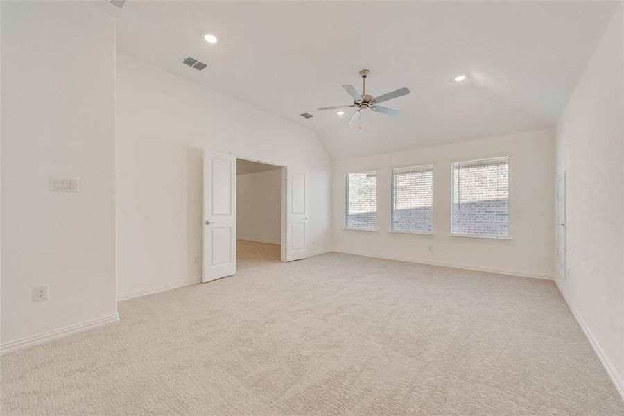 Spare room featuring lofted ceiling, light colored carpet, and ceiling fan