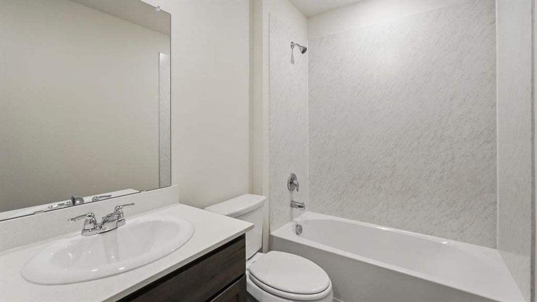 Bathroom featuring a dark wood-finish vanity, white countertop, integrated sink, and a mirrored wall