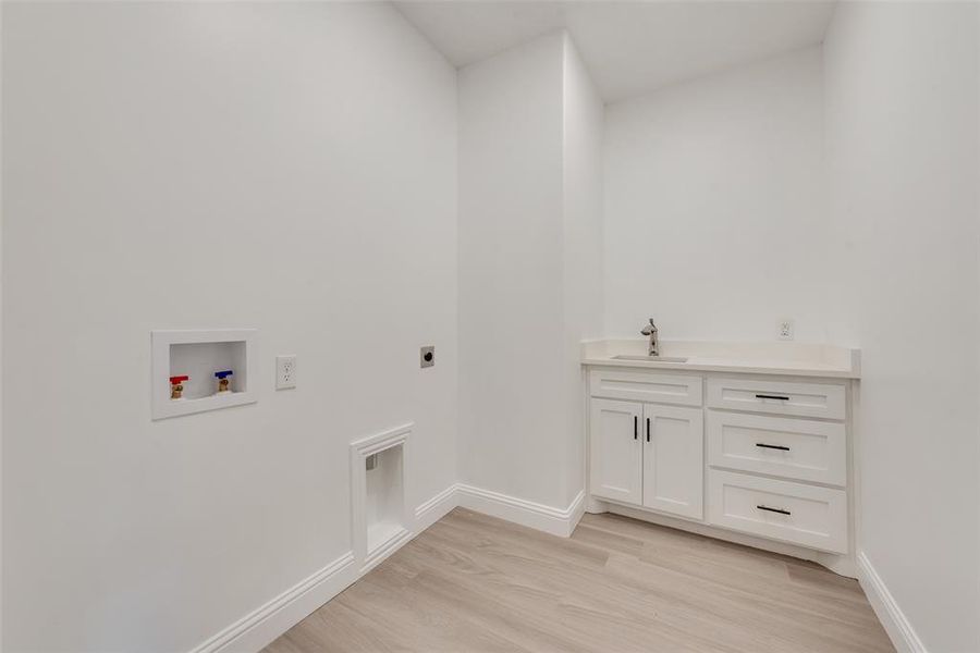 Laundry room featuring light wood-style floors, hookup for a washing machine, cabinet space, and electric dryer hookup Laundry room featuring light wood-style floors, hookup for a washing machine, cabinet space, and electric dryer hookup